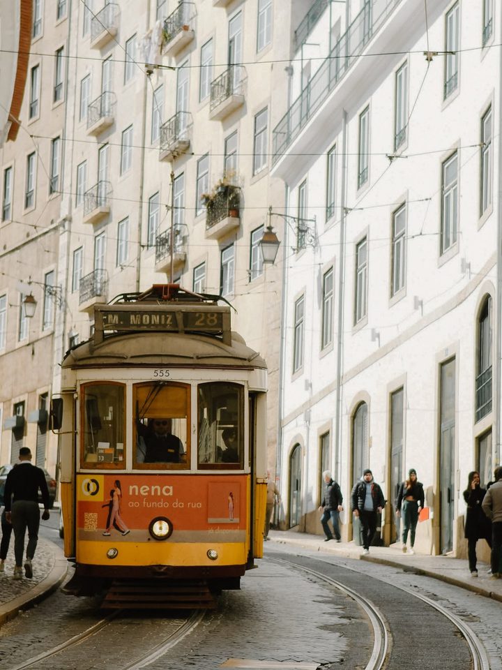 A yellow tram climbing a street in Lisbon
